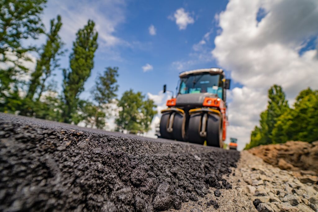 road roller flattening new asphalt. Heavy Vibration roller at work paving asphalt, road repairing. Selective focus.